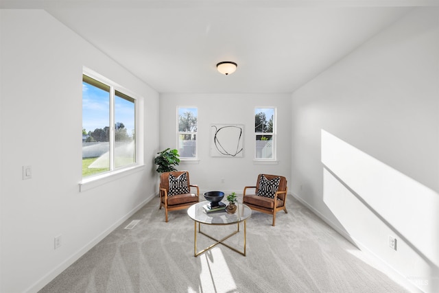 living area with baseboards and light carpet