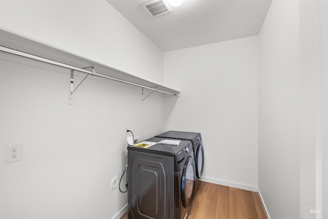 laundry area with wood finished floors, baseboards, and washing machine and dryer