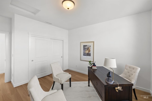 home office featuring attic access, light wood-type flooring, and baseboards