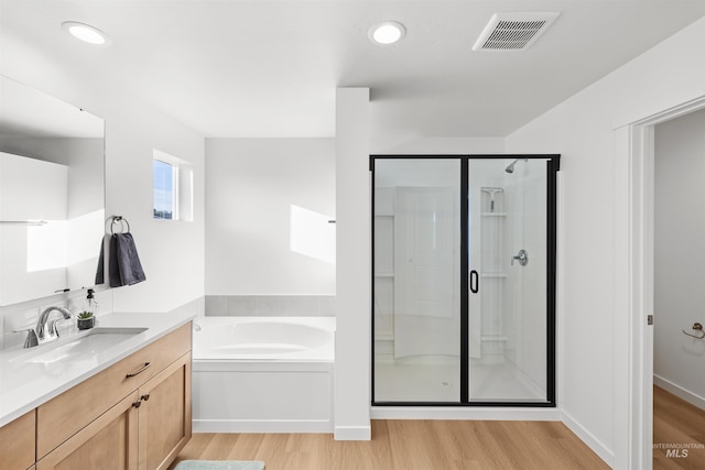 full bathroom with wood finished floors, a shower stall, a garden tub, vanity, and recessed lighting