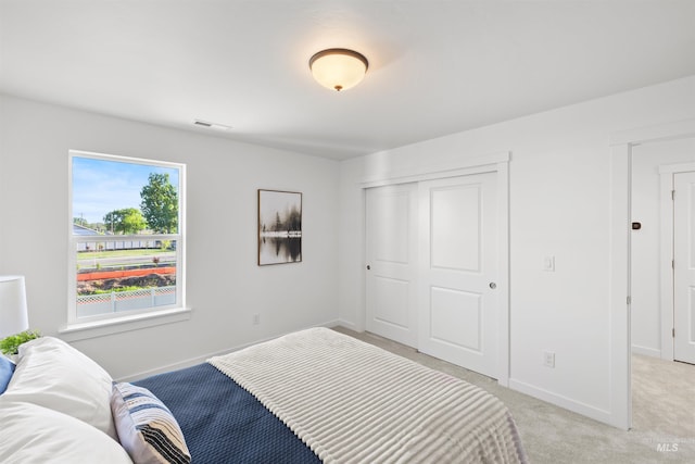 bedroom featuring baseboards, a closet, and light colored carpet