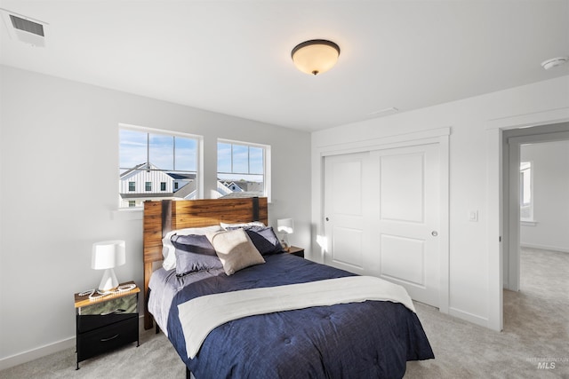 bedroom featuring light colored carpet, a closet, and baseboards
