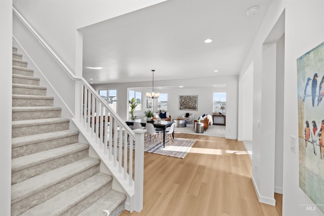 stairway featuring wood finished floors, healthy amount of natural light, a chandelier, recessed lighting, and baseboards