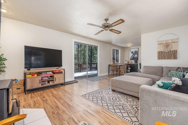living room with light wood-style floors, ceiling fan, and baseboards