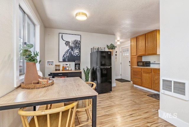 kitchen featuring visible vents, light countertops, light wood-style floors, a textured ceiling, and black appliances