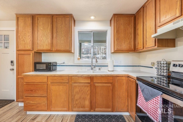 kitchen featuring a sink, light countertops, electric stove, under cabinet range hood, and black microwave