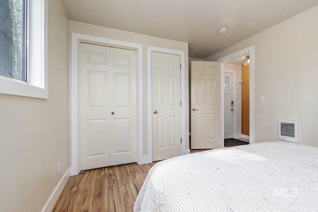 bedroom with light wood finished floors, baseboards, and heating unit