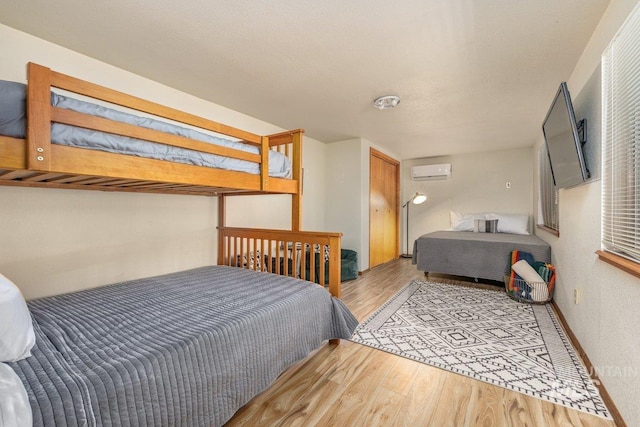 bedroom with a wall mounted AC and wood finished floors