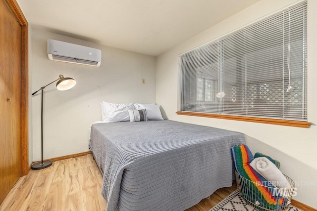 bedroom featuring baseboards, wood finished floors, and a wall unit AC