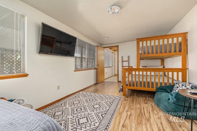 bedroom with a textured ceiling, wood finished floors, and baseboards