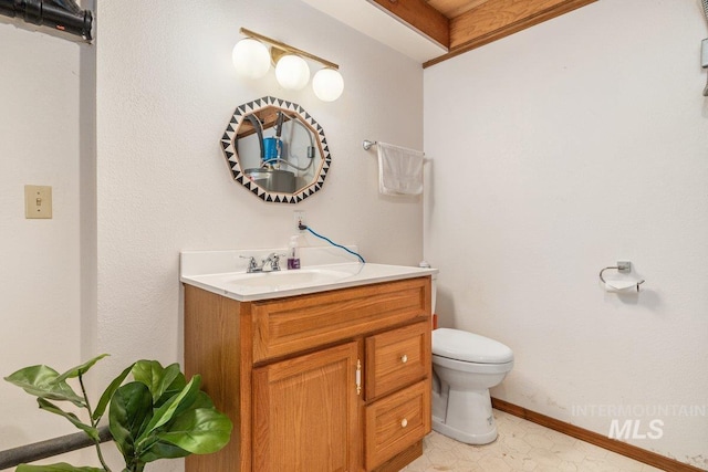 half bathroom featuring toilet, vanity, and baseboards