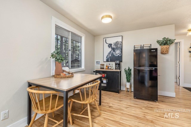 dining space featuring light wood-type flooring and baseboards