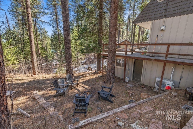 view of yard featuring ac unit, a wooden deck, and a fire pit