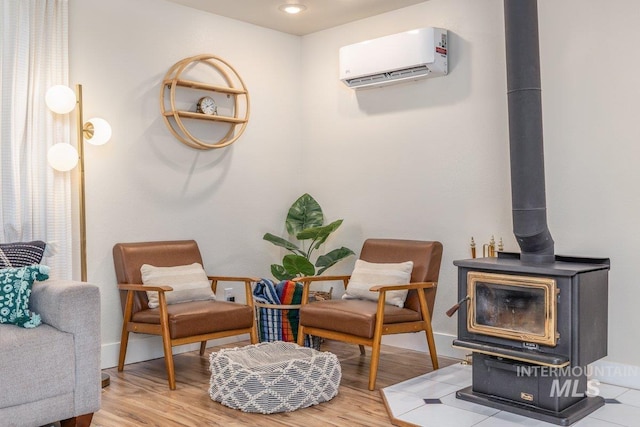 living area featuring a wood stove, an AC wall unit, baseboards, and wood finished floors