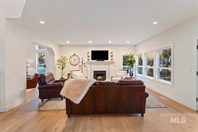 living area with light wood-style flooring, a lit fireplace, baseboards, and recessed lighting