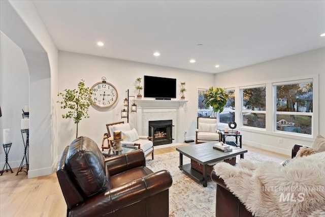 living room with a fireplace with flush hearth, recessed lighting, baseboards, and light wood finished floors