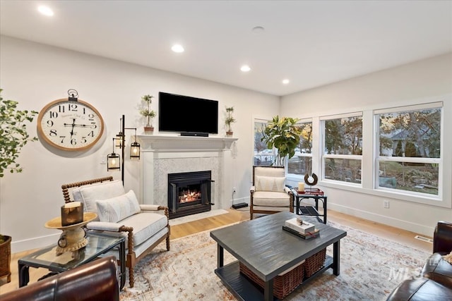 living area featuring a fireplace with flush hearth, baseboards, wood finished floors, and recessed lighting