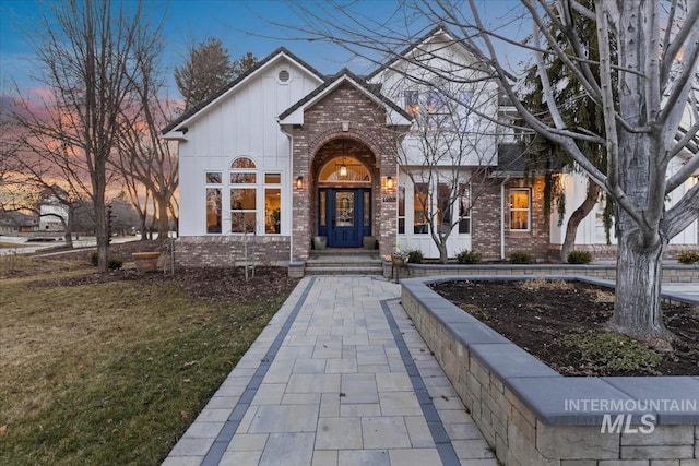 view of front facade featuring board and batten siding, a front yard, and brick siding