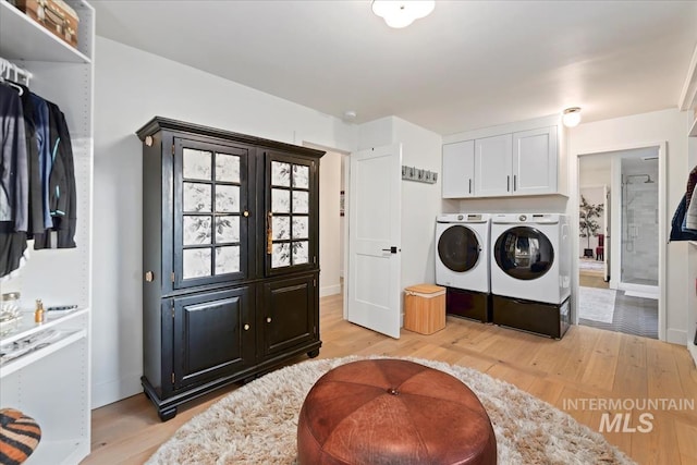 laundry room with separate washer and dryer, cabinet space, and light wood-style flooring