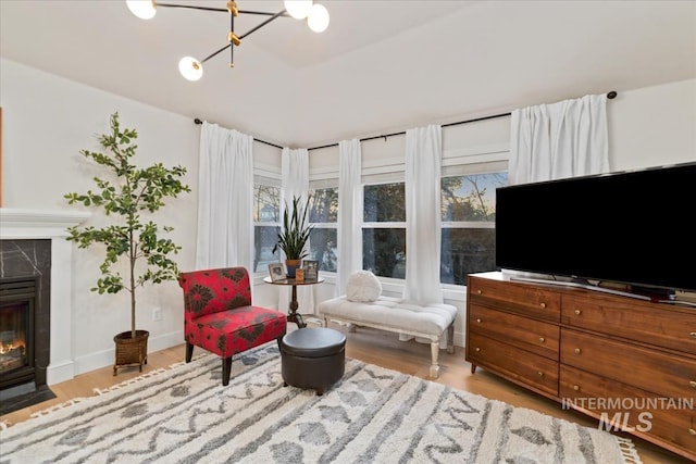 sitting room featuring a tile fireplace, an inviting chandelier, wood finished floors, and baseboards