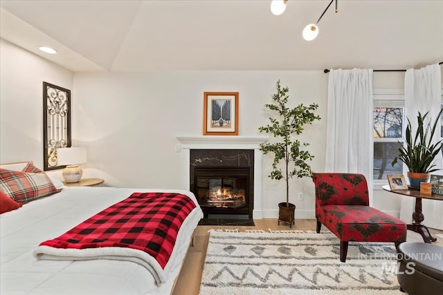 bedroom with baseboards, a premium fireplace, wood finished floors, and recessed lighting