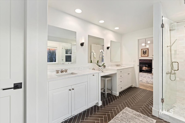 bathroom with a shower stall, vanity, a glass covered fireplace, and recessed lighting