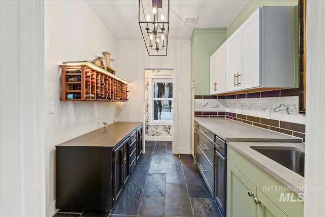 kitchen with visible vents, white cabinetry, light countertops, hanging light fixtures, and backsplash