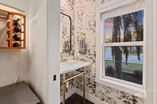 bathroom with baseboards, a sink, and wallpapered walls