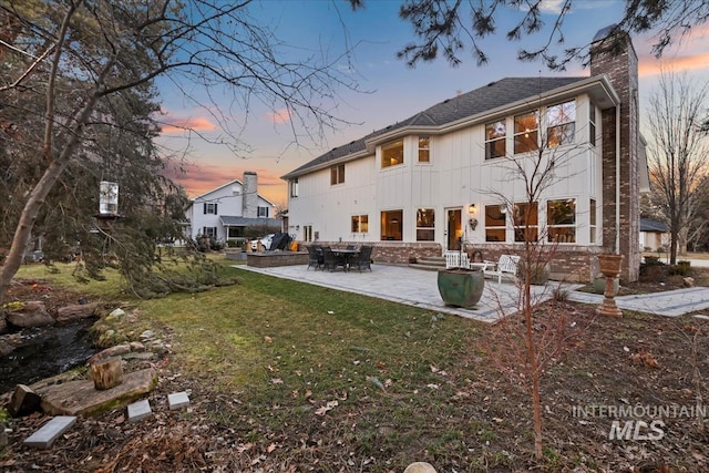 rear view of property featuring a patio, a chimney, and a lawn