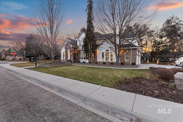 view of front of home featuring a residential view, brick siding, and a lawn