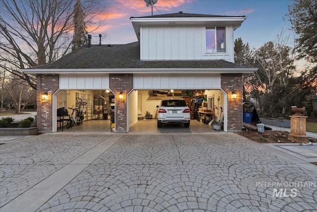 exterior space featuring board and batten siding, decorative driveway, and brick siding