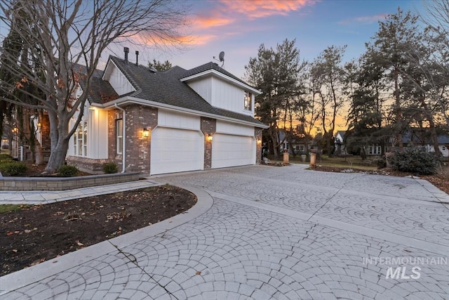 view of property exterior with roof with shingles, brick siding, decorative driveway, and an attached garage