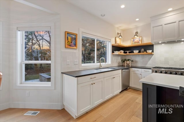 kitchen featuring visible vents, decorative backsplash, light wood-type flooring, open shelves, and a sink