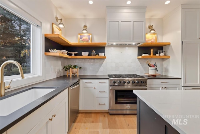 kitchen featuring premium appliances, a sink, white cabinetry, light wood-style floors, and open shelves