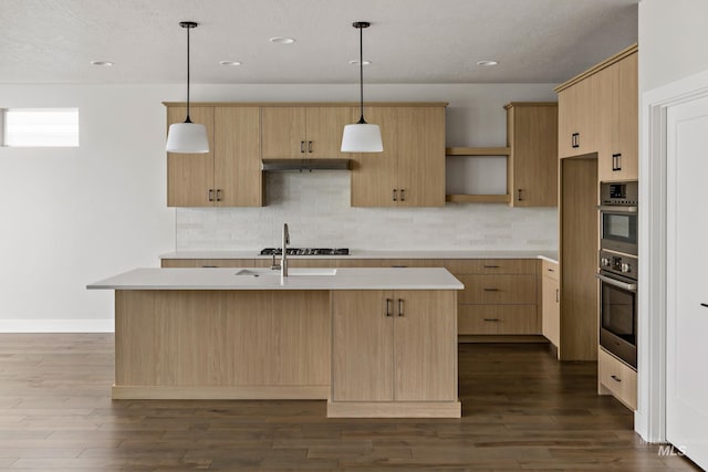 kitchen featuring a kitchen island with sink, decorative light fixtures, light countertops, and light brown cabinets