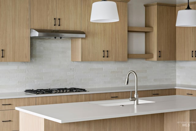 kitchen with open shelves, under cabinet range hood, light countertops, pendant lighting, and stainless steel gas stovetop