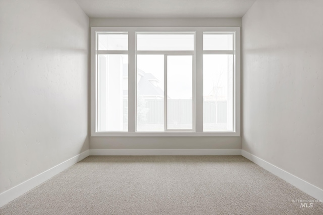 carpeted empty room featuring baseboards