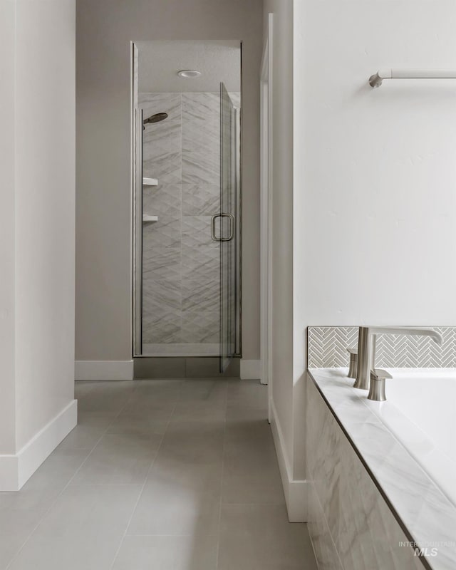 bathroom featuring a shower stall, baseboards, and tile patterned floors