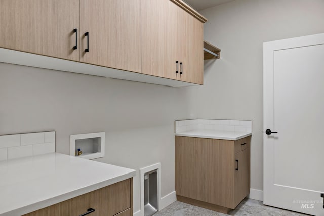 clothes washing area with baseboards, cabinet space, and washer hookup