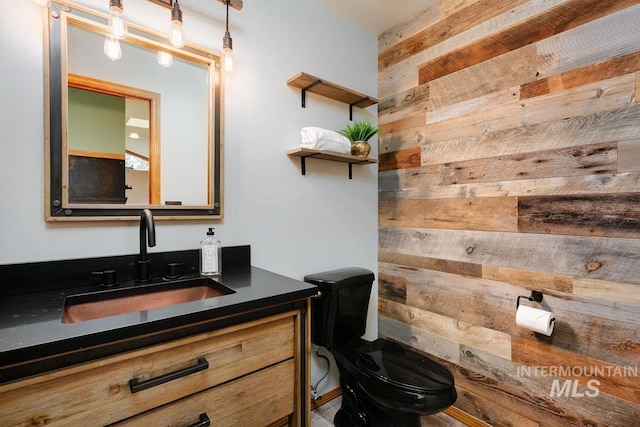 bathroom with wood walls, vanity, and toilet