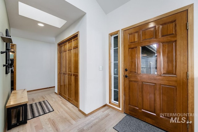 foyer entrance with light wood-type flooring and a skylight