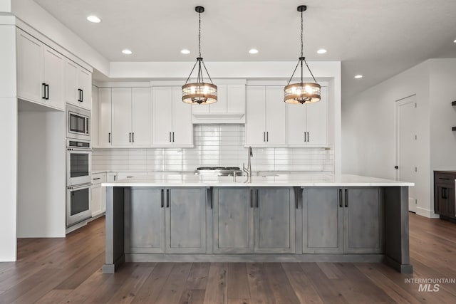 kitchen featuring appliances with stainless steel finishes, backsplash, hanging light fixtures, white cabinets, and sink