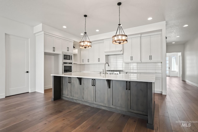 kitchen with a spacious island, white cabinetry, appliances with stainless steel finishes, and hanging light fixtures