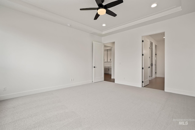 empty room with carpet floors, a raised ceiling, and ceiling fan