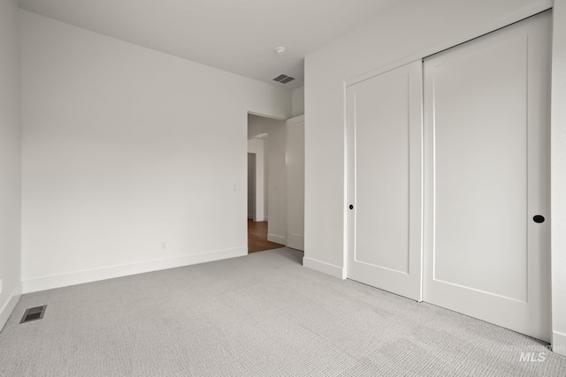 unfurnished bedroom with light colored carpet and a closet