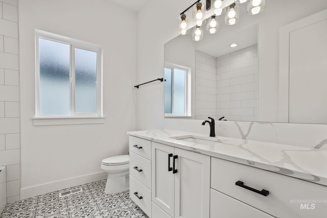 bathroom with toilet, vanity, and tile patterned flooring