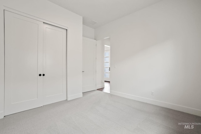 unfurnished bedroom featuring light carpet and a closet