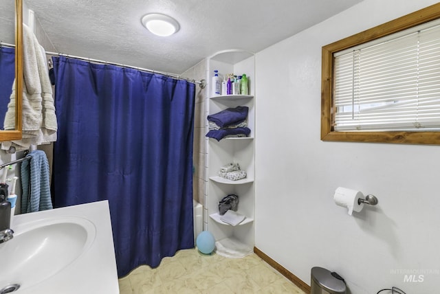 bathroom featuring shower / bath combo, a textured ceiling, and sink