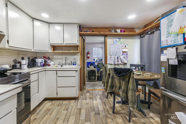 kitchen with white cabinets, stainless steel range with electric stovetop, sink, and tasteful backsplash