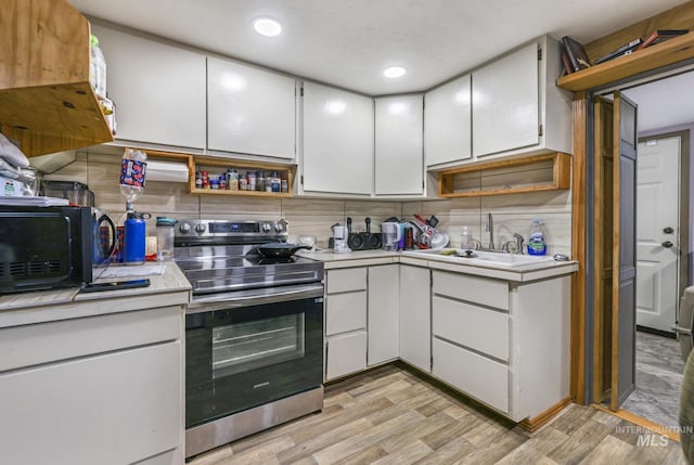 kitchen with white cabinets, sink, light hardwood / wood-style flooring, stainless steel electric range oven, and tasteful backsplash